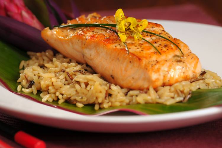 Seared fish on a bed of rice served on a banana leaf