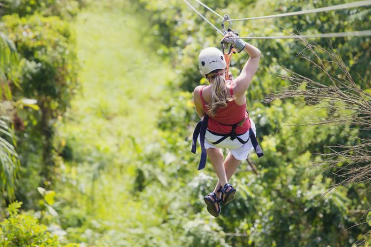 A women ziplines through a jungle