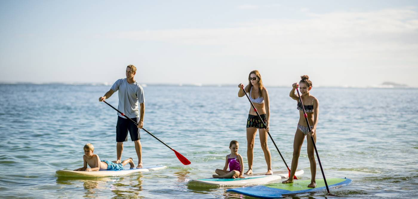 A family of 5 paddle board on calm waters in Hawaii